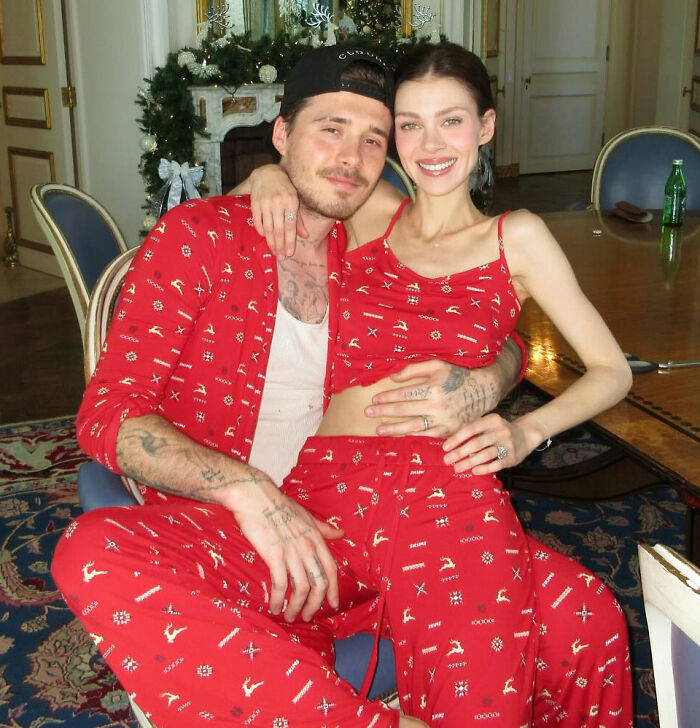 Brooklyn Beckham wearing matching red pajamas with partner in a cozy indoor setting during a family feud period.