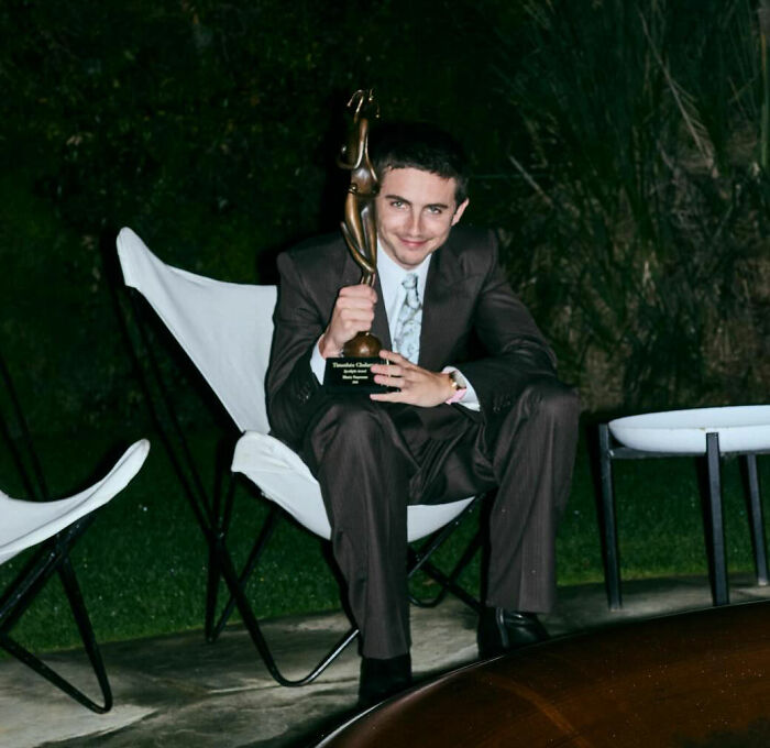 Man in dark suit holding award and smiling while seated outdoors, fans point out sad detail involving Timothée Chalamet and Kylie Jenner Man in dark suit holding award and smiling while seated outdoors, fans point out sad detail involving Timothée Chalamet and Kylie Jenner