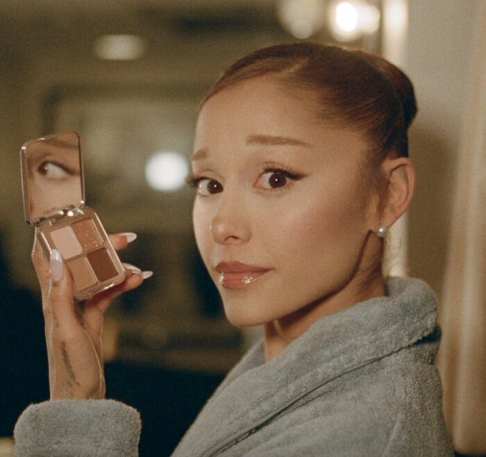 Ariana Grande holding a makeup palette, showcasing her bizarre mannerisms in a recent unsettling interview.