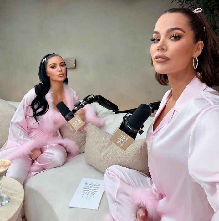 Two women in pink outfits recording a podcast discussing Prince Harry and Meghan Markle after photos vanished controversy.