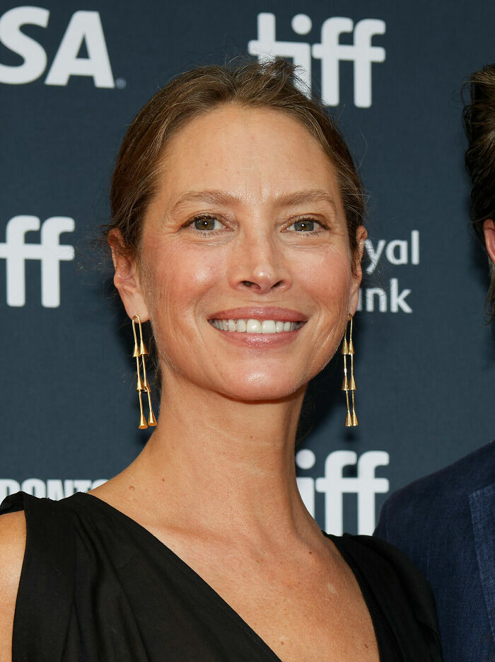 Christy Turlington smiling at a film festival event, wearing gold earrings and a black dress.
