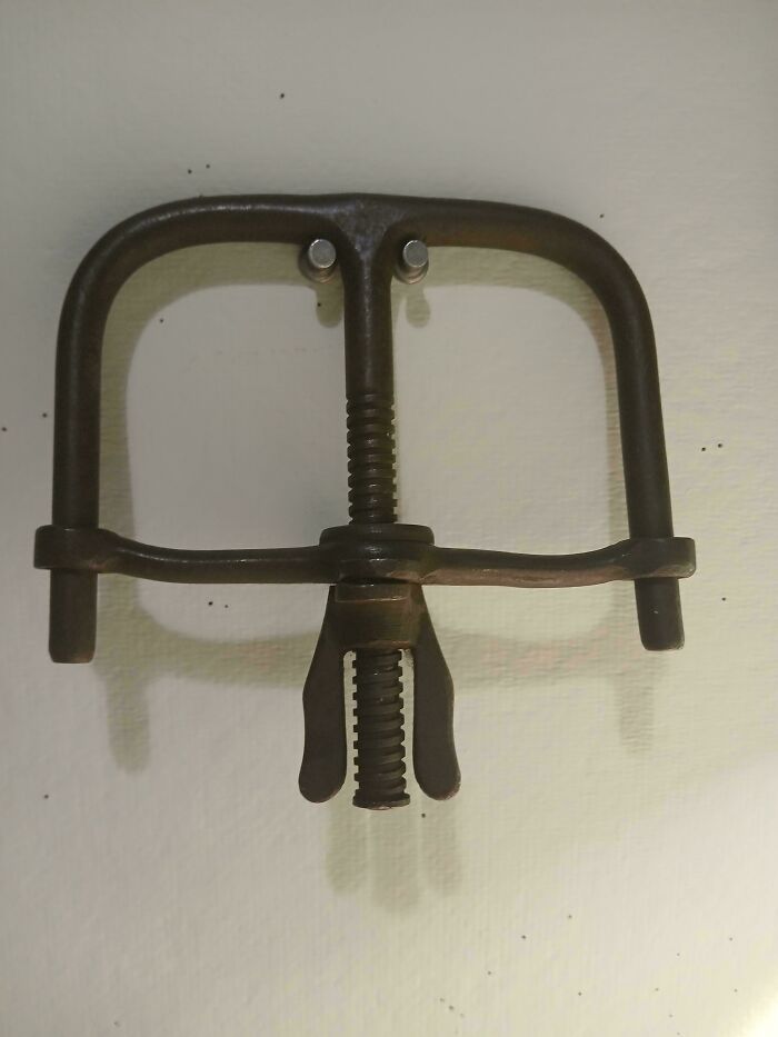 Rusty vintage metal tool with mechanical s***w clamp, an interesting but creepy object that might fascinate and disturb viewers