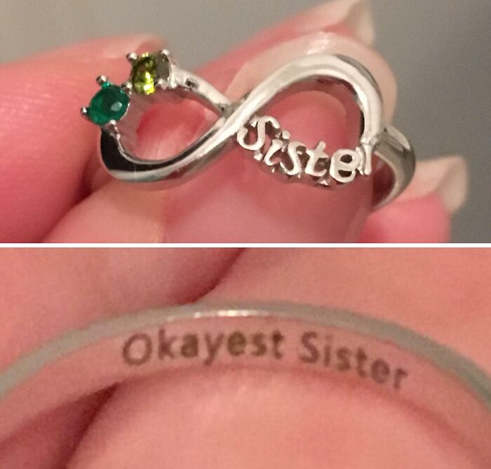 Silver infinity ring with green stones and the word Sister, engraved inside with Okayest Sister, celebrating siblings.
