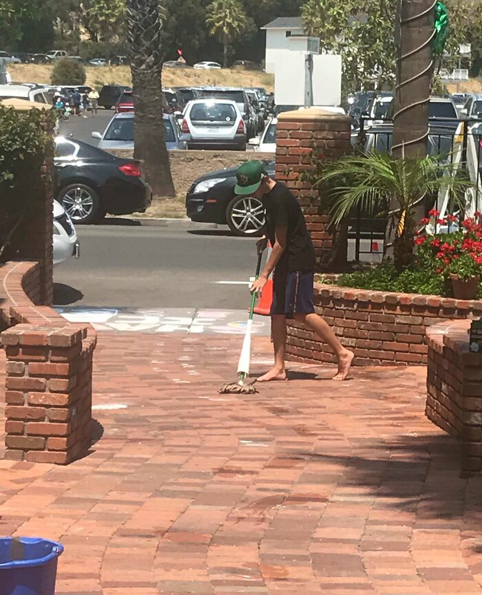 Boy mopping a brick patio on a sunny day, showing everyday life moments that prove life is more fun with siblings.