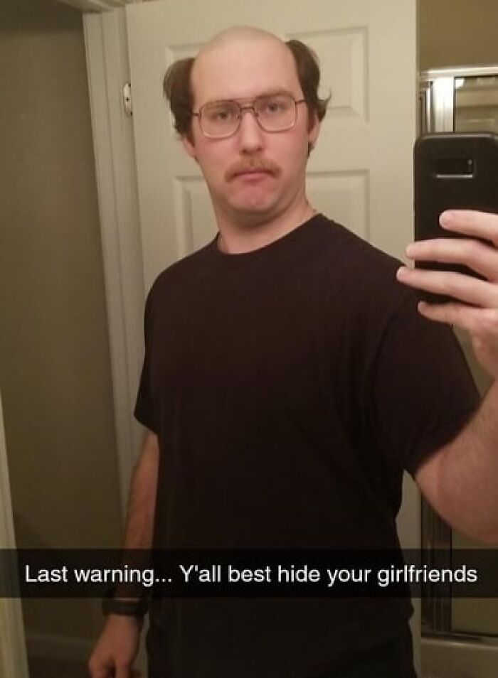 Man with glasses and a mustache taking a mirror selfie with a humorous caption about siblings and girlfriends.