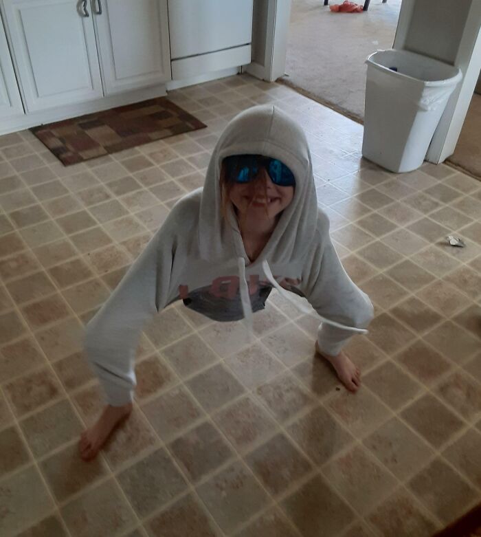 Child wearing hoodie and sunglasses playfully balancing on hands and feet, showing how life is more fun with siblings.