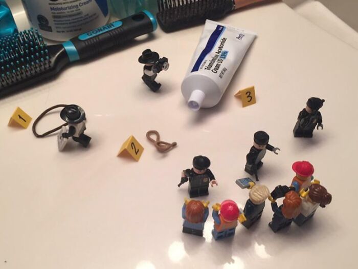 Miniature LEGO figures staged in a playful crime scene setup showing siblings having fun with toys and creativity.