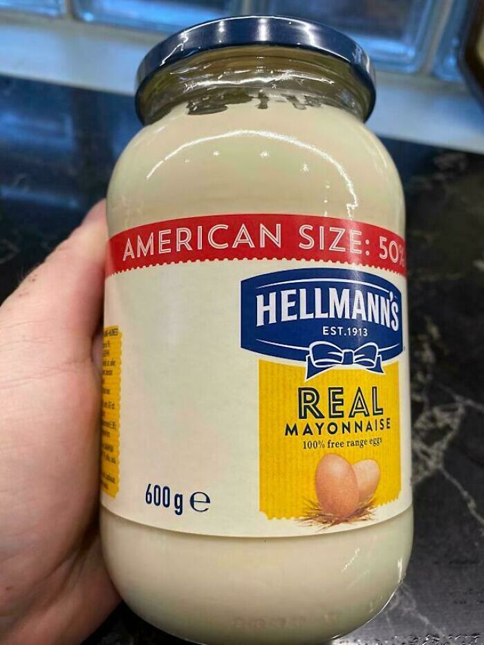 Hand holding a 600g jar of Hellmann's real mayonnaise labeled American size, showcasing impressive country packaging.