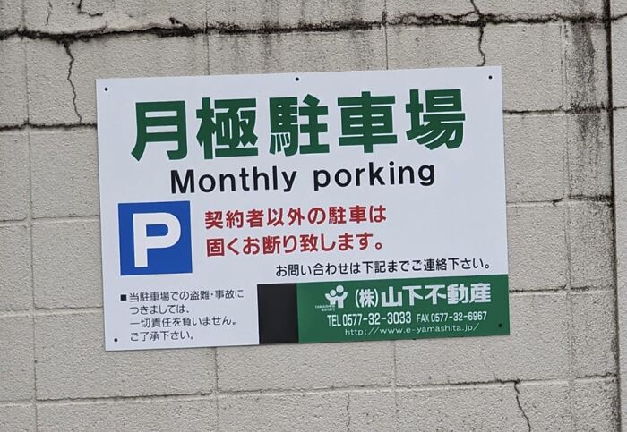 Monthly parking sign in Japan humorously mistranslated as Monthly porking on a c*****d wall background.