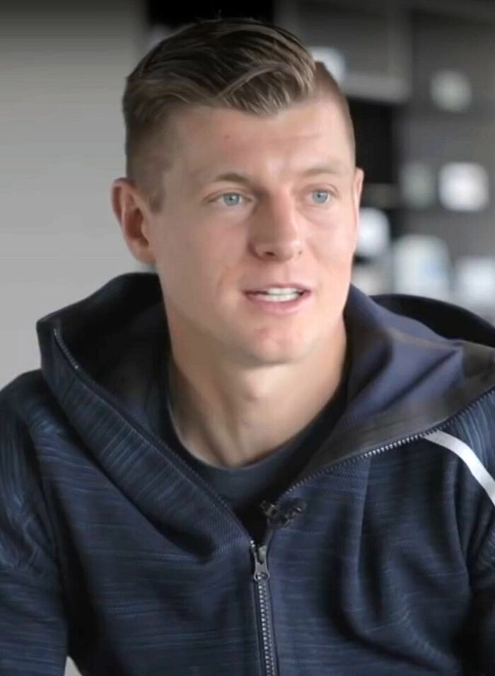 Toni Kroos speaking during an interview, wearing a dark zip-up jacket with a casual indoor background.