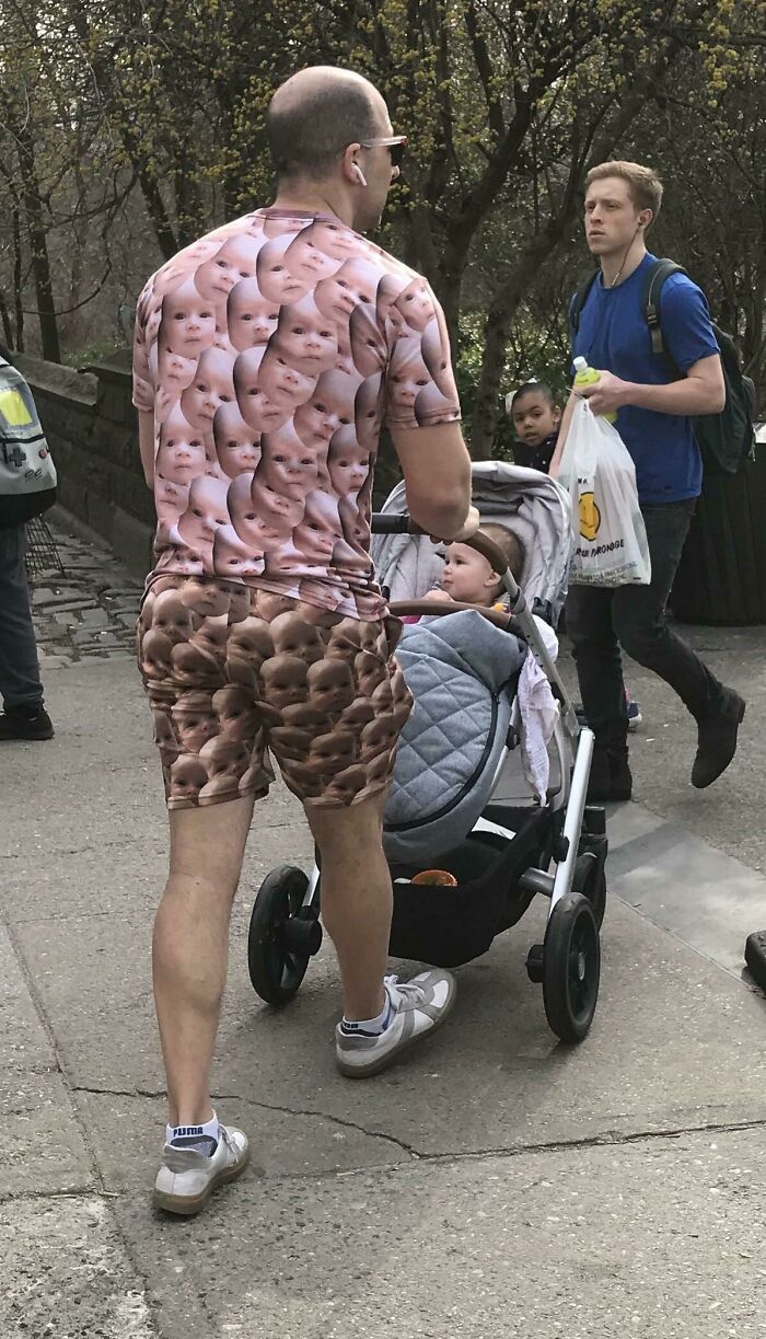 Man wearing matching shirt and shorts covered in baby face prints pushing a stroller, a funny example of hilarious fashion fails.