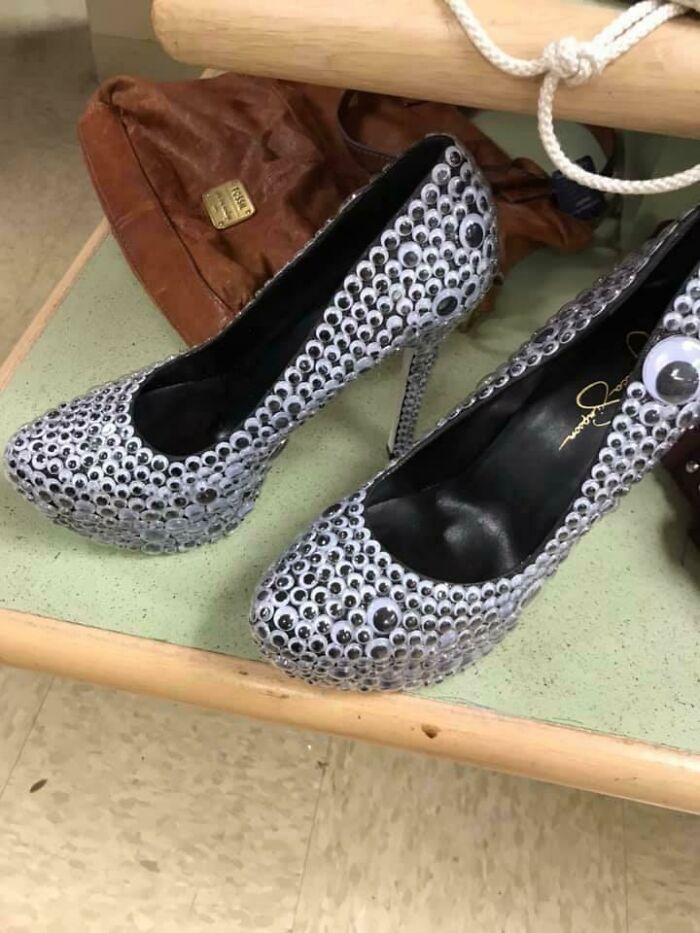 High heels covered in googly eyes sitting on a table next to a brown bag showcasing hilarious fashion fails.