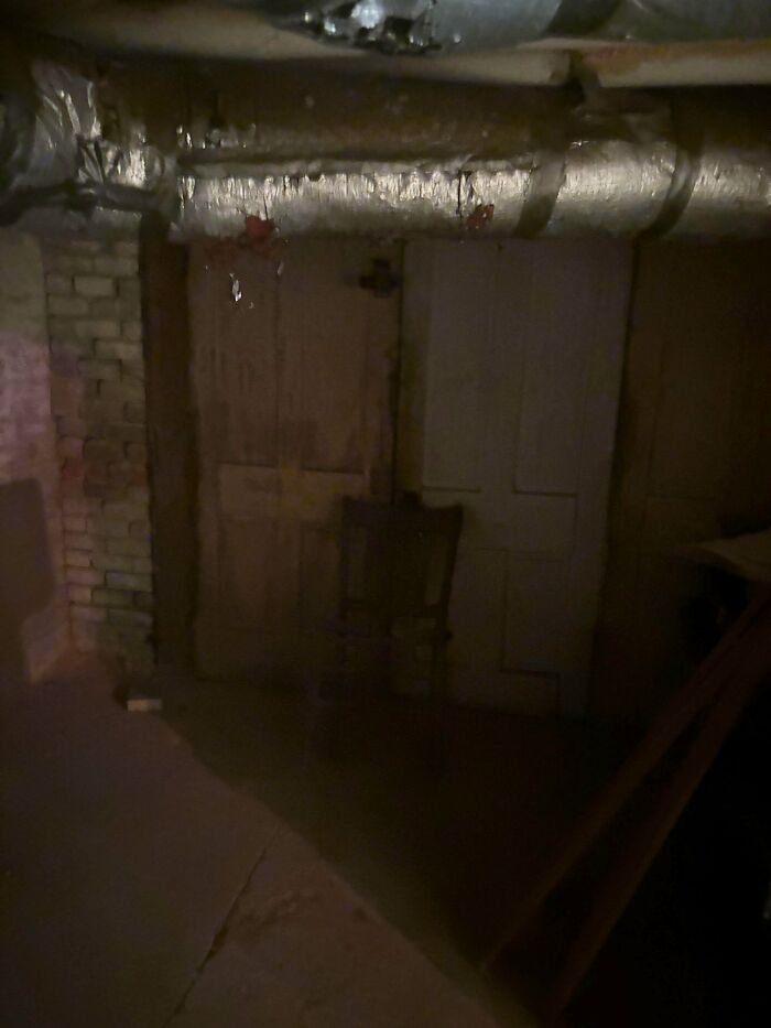 Sótano oscuro con una silla antigua frente a puertas viejas, ambiente inquietante que recuerda publicaciones de miedo y realidad.