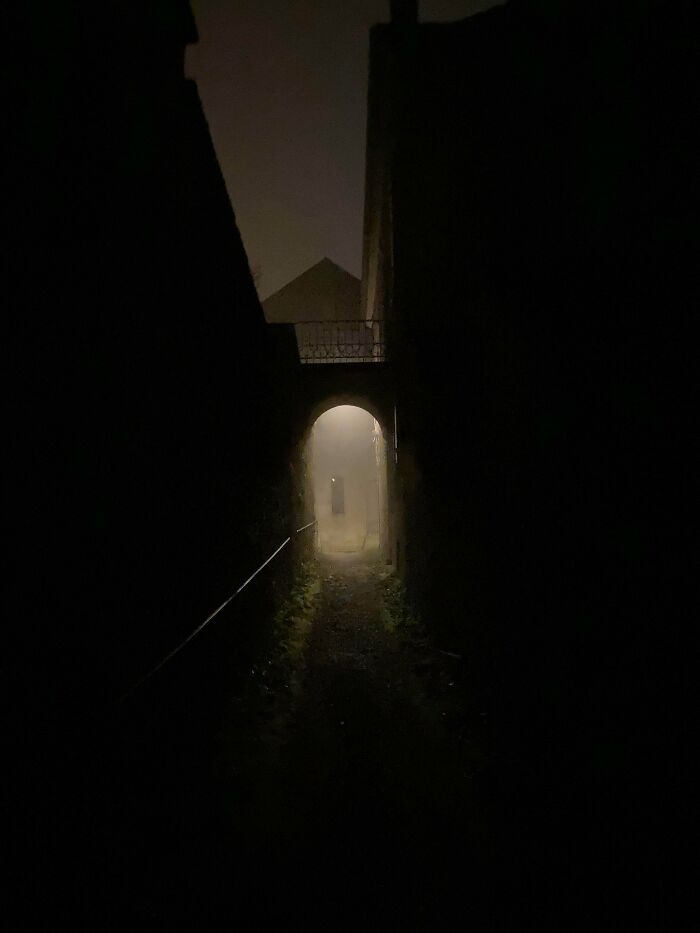Pasaje oscuro y tenebroso con niebla, creando una atmósfera inquietante que invita a cuestionar la realidad.