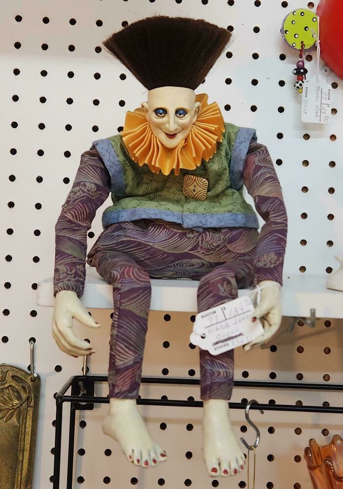 Creepy doll with exaggerated hair and colorful outfit sitting on shelf, embodying the scariest posts shared online theme.
