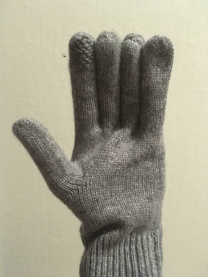 Gray knitted glove with a noticeably shorter pinky finger, illustrating a hilarious fashion fail in accessory design.