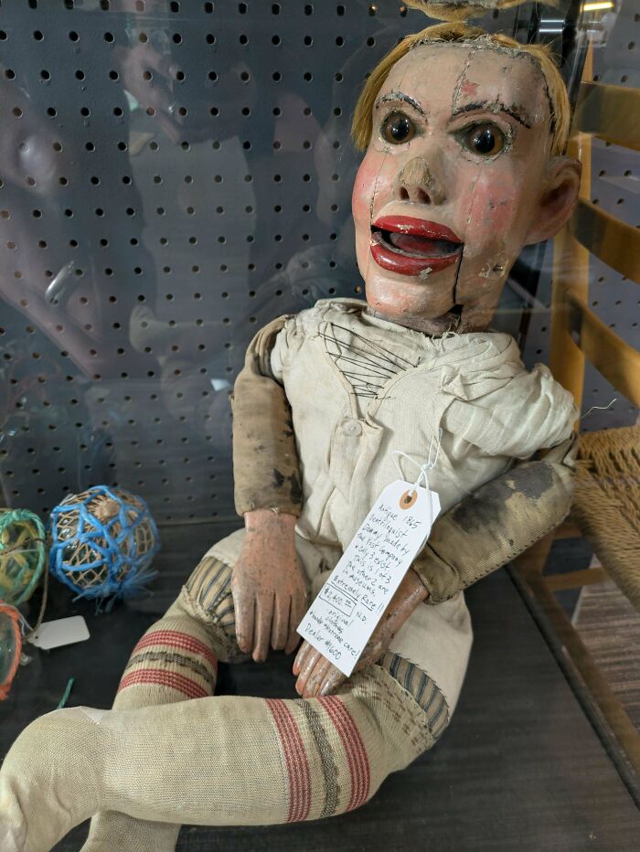 Antique creepy ventriloquist dummy with worn clothes and a handwritten tag, evoking scary posts shared online.