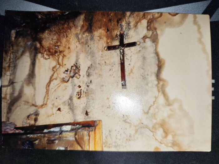 Stained and moldy wall with a hanging wooden crucifix, evoking eerie and scary posts shared online atmosphere.