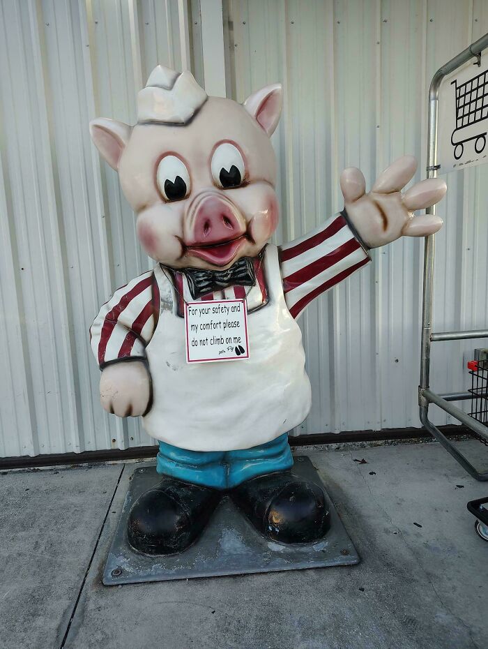Statue of a cartoon pig mascot with a warning sign, featured among scary posts shared online.