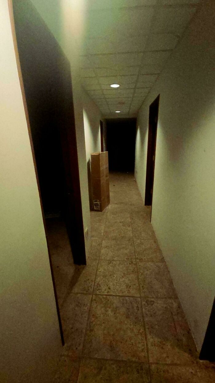Dimly lit empty hallway with doors and a dark end, creating a spooky and scary atmosphere in the space.