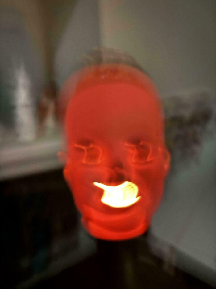 Blurry glowing red face with distorted features and bright light in the mouth, evoking scary posts shared online.