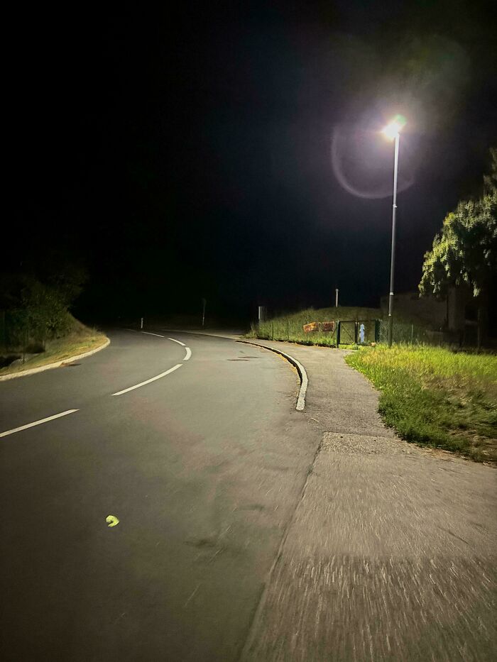 Dark empty street at night illuminated by a streetlamp, evoking a sense of eerie and scary posts shared online.
