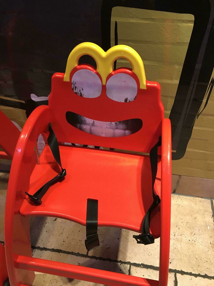 Red plastic children's chair with frightening eyes and mouth design, creating a scary online post visual effect.