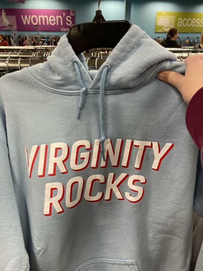 Light blue hoodie with bold red and white text saying Virginity Rocks, held up in a women's clothing store, a hilarious fashion fails example.