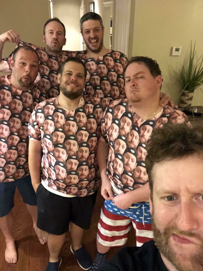 Group of men wearing matching shirts covered with a face print, posing indoors as a hilarious fashion fails example.