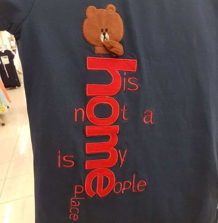 Navy shirt with confusing red text design and a stuffed bear head, showcasing a hilarious fashion fail.