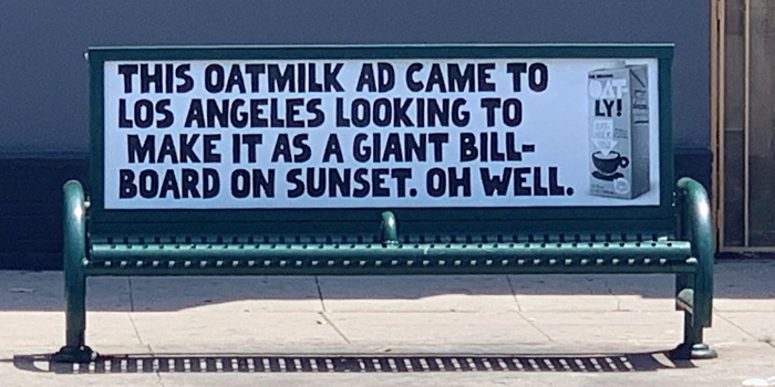 Oatmilk print advertisement using humor and creativity on a bench to stand out from competitors.