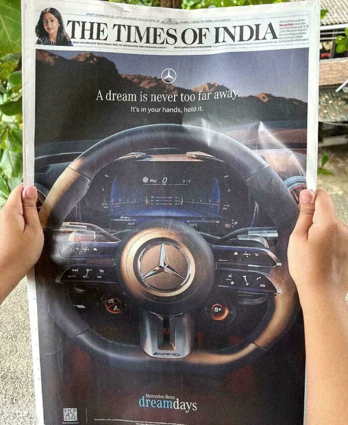 Creative print advertisement showing a Mercedes-Benz steering wheel blending with a newspaper for humorous impact