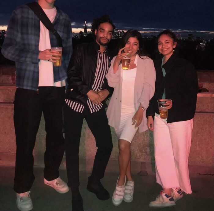 Group of four friends at night with drinks, highlighting height difference as a common struggle tall people face.