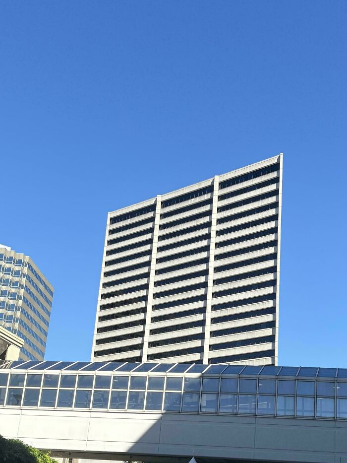 High-rise office tower and glass skybridge under clear blue sky, glitches in the matrix