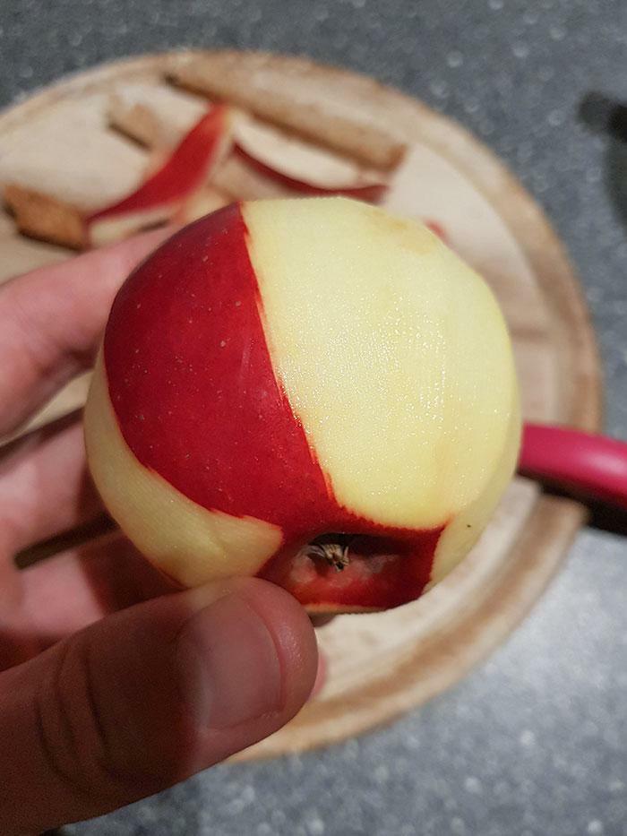 Partially peeled red apple held over cutting board with oddly patterned skin, glitches in the matrix