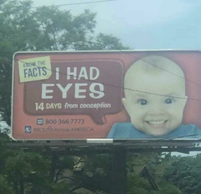 Billboard print advertisement using humor and creativity featuring a baby with an oversized smiling face and text about early eye development.