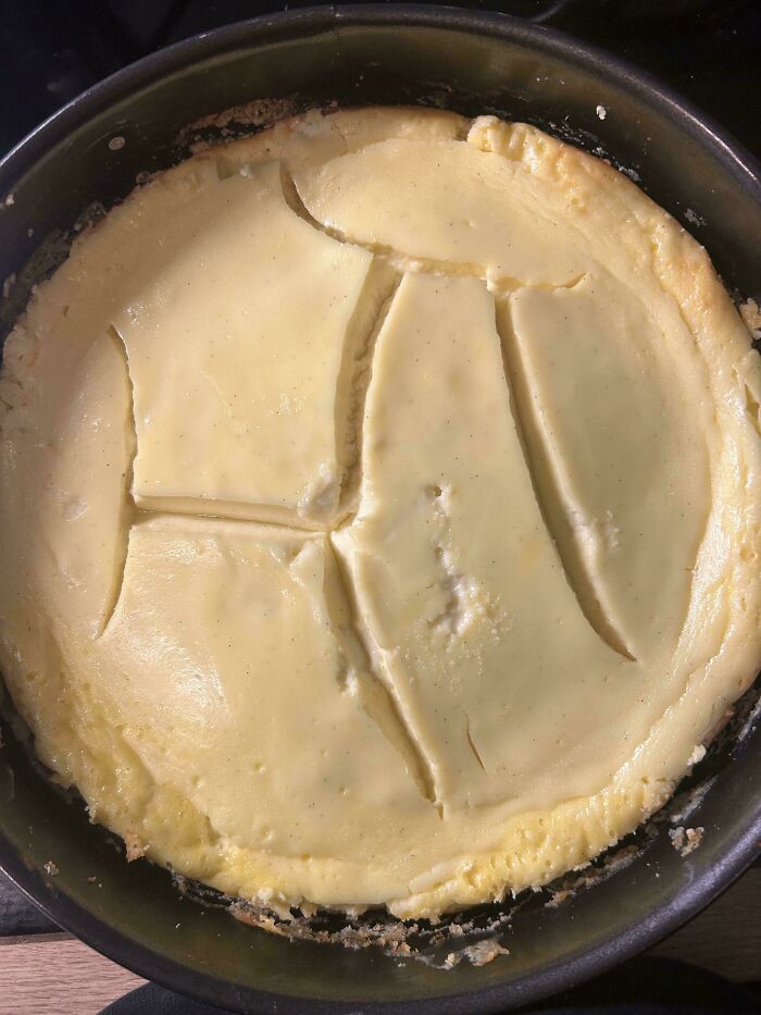 C*****d and uneven cheesecake in a pan showing a common example of ruined dessert mishaps.