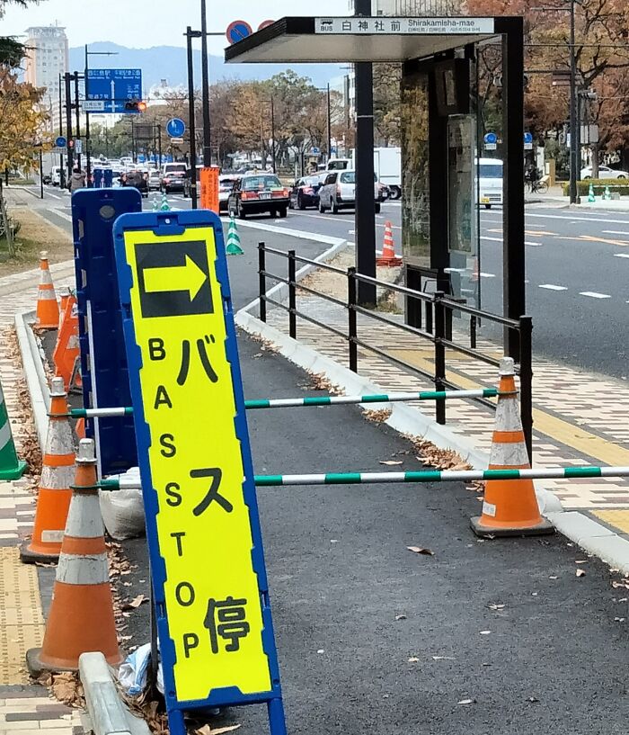 Bus stop sign with Japanese characters and English letters showing a mistranslation, illustrating Japan lost in English translation.