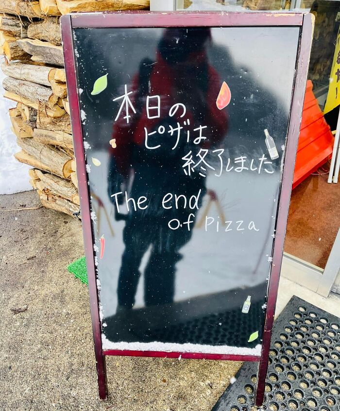 Chalkboard outside store with funny English translation saying The end of pizza in Japan translation fails.