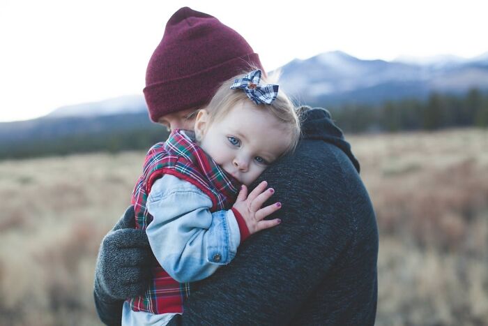 Adult holding a toddler outdoors in winter clothing, capturing a tender moment related to family secrets.