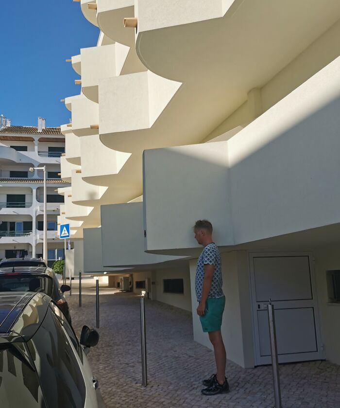 A tall person standing uncomfortably close to a low overhang, illustrating struggles tall people face outdoors.