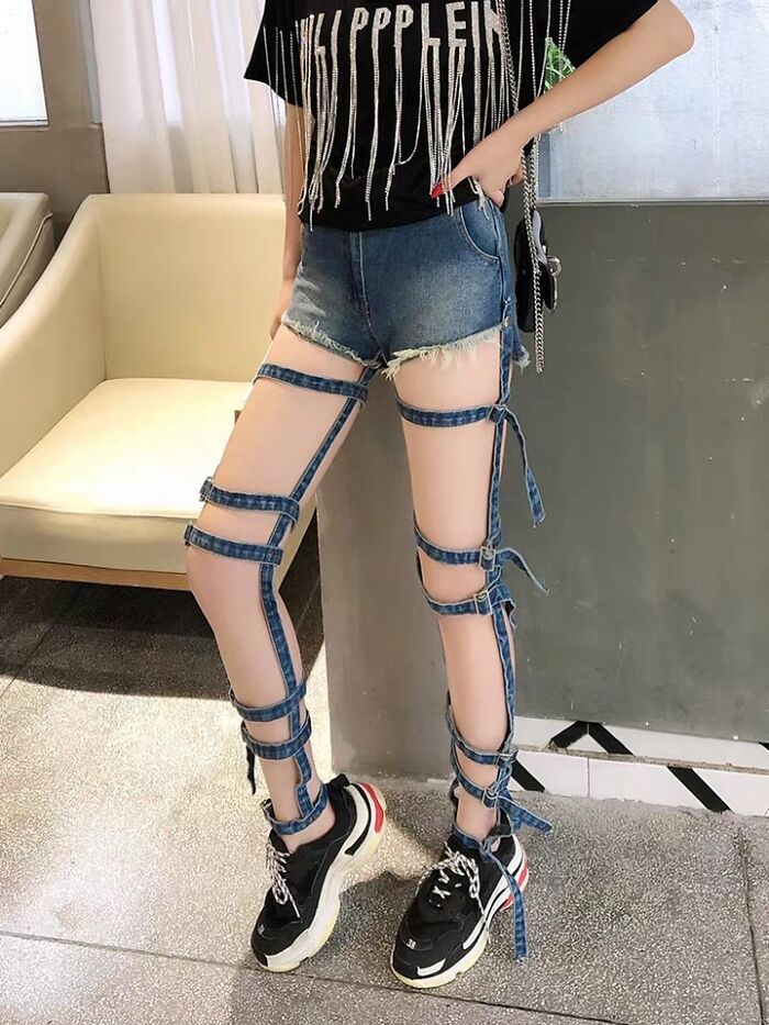 Person wearing denim shorts with multiple denim straps wrapped around legs and chunky black sneakers in a hilarious fashion fails look