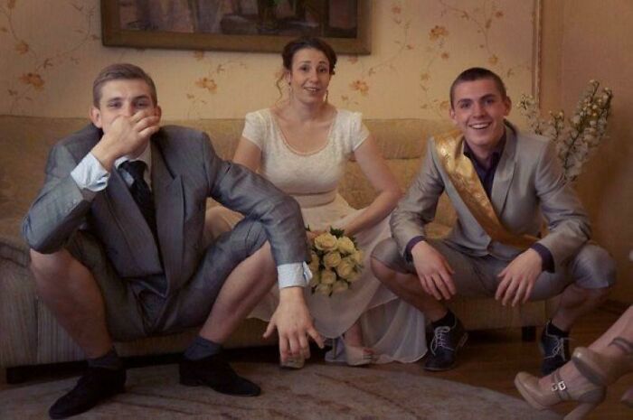 Three people in formal wedding attire posing awkwardly, capturing one of the most awkward wedding photos moments.
