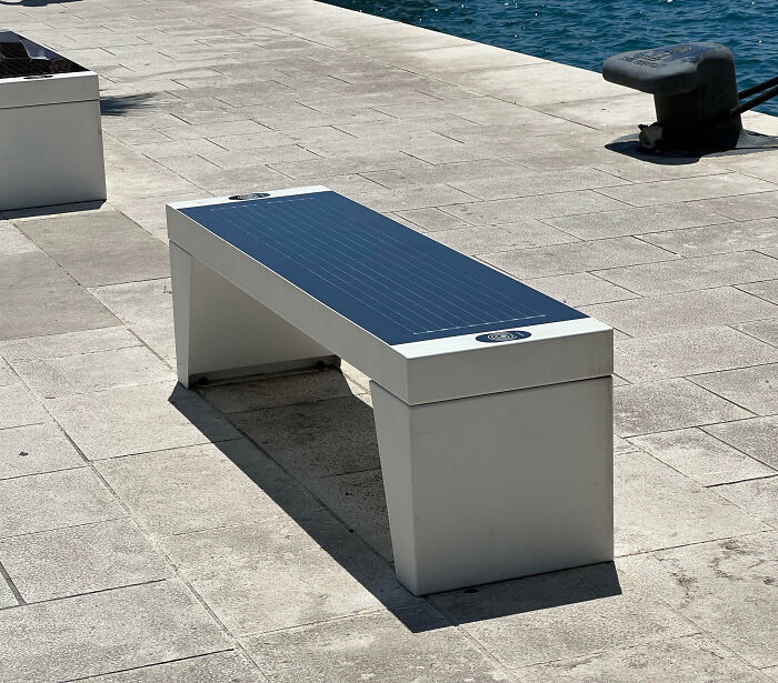Solar-powered public bench on a waterfront, an impressive thing countries implemented to enhance urban spaces and sustainability.