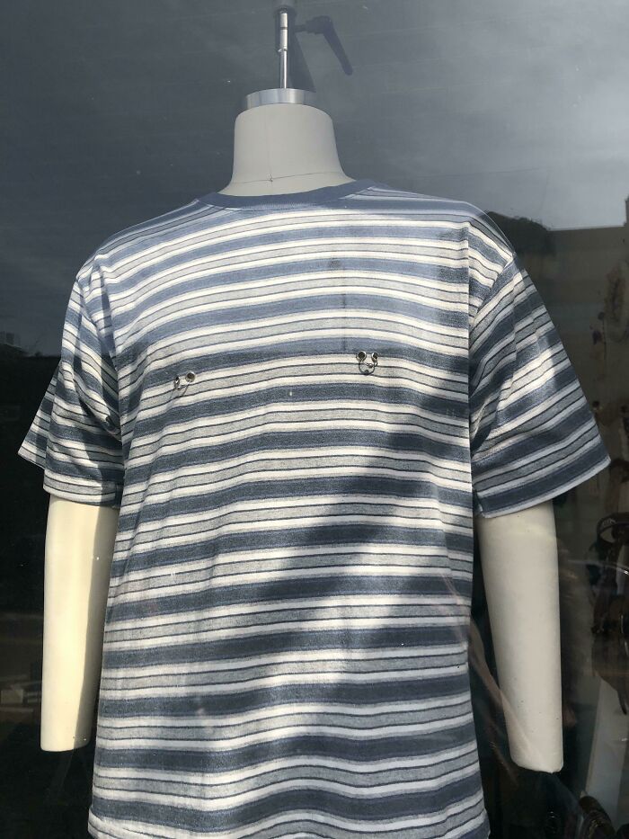Striped t-shirt on a mannequin with misplaced grommets near the chest area, showcasing hilarious fashion fails.