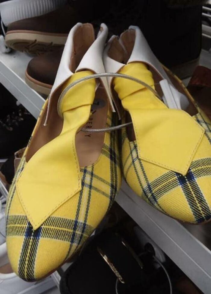 Yellow plaid shoes with mismatched designs and an unusual fastening, showcasing a hilarious fashion fail on a store shelf.