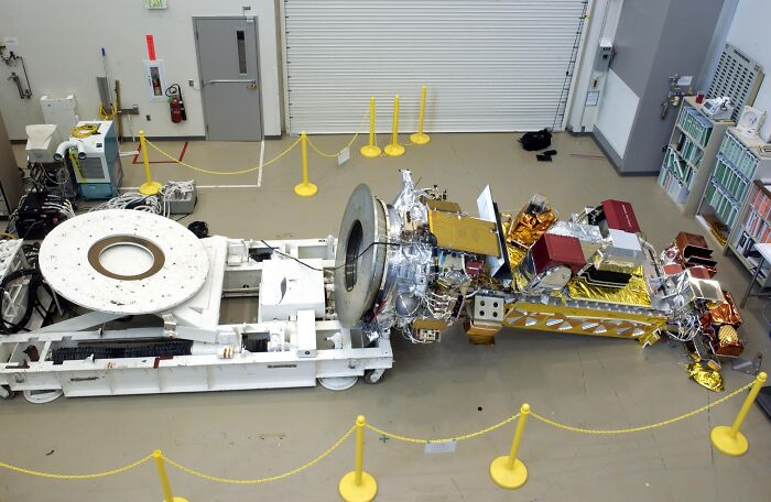 Damaged complex machinery inside a workshop, surrounded by yellow barriers as an expensive fail in an industrial setting.