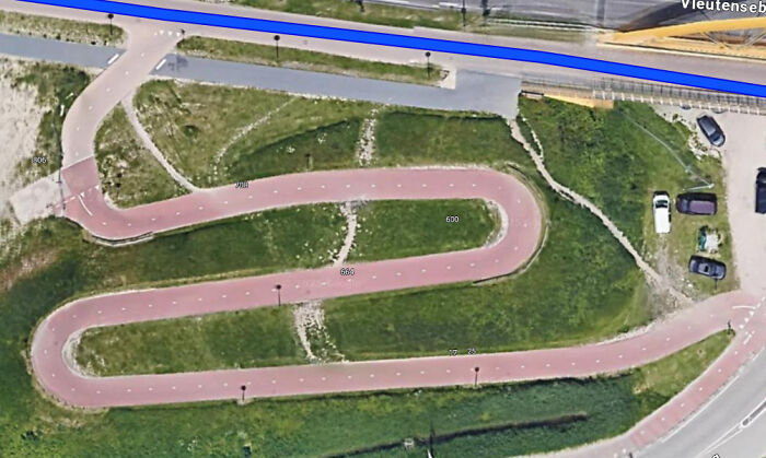 Aerial view of desire paths cutting through a green area beside a curved city bike path, showing urban planning vs reality.
