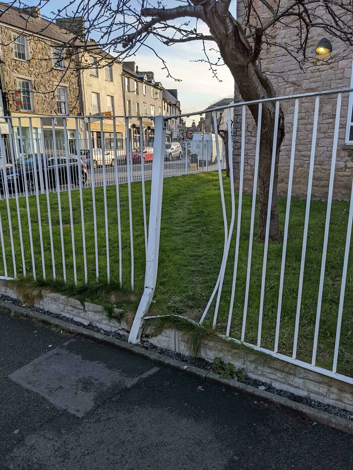 Worn desire path through grass shows how people walk despite fencing and city planning barriers.