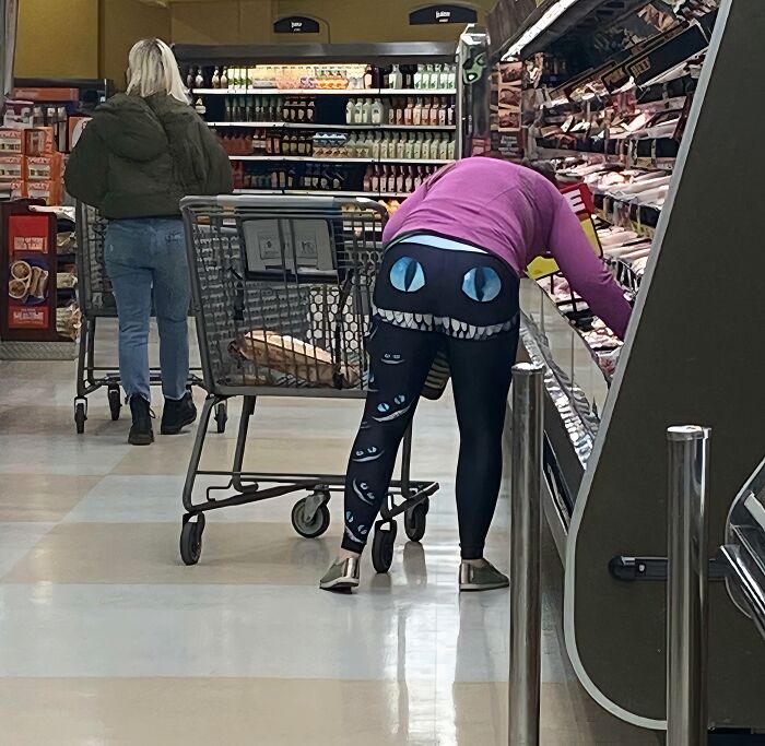 Person wearing black leggings with large cartoon eyes and teeth design shopping in a grocery store, showcasing hilarious fashion fails. Person wearing black leggings with large cartoon eyes and teeth design shopping in a grocery store, showcasing hilarious fashion fails.